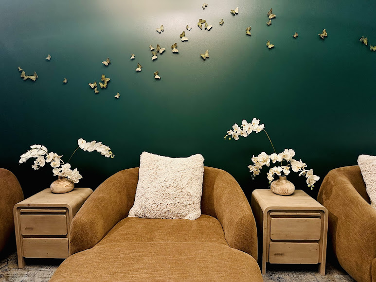 Caramel lounge chairs against a deep teal wall with butterfly art at EvolvE